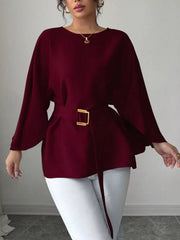 Wine red belted blouse with batwing sleeves and gold buckle detail.
