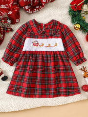 Red plaid baby dress with smocked Santa and reindeer detail, long sleeves, and Peter Pan collar.
