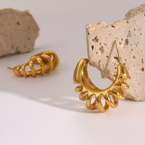 Sculptural ribbed gold hoop earrings with a unique, open design.