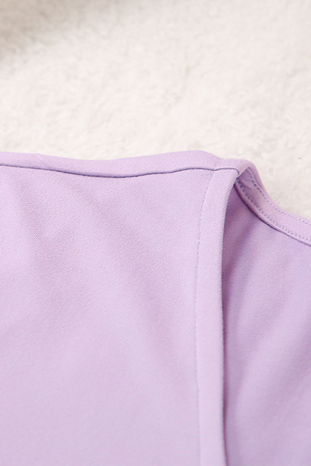 Draped wrap top detail in soft lilac purple fabric with clean stitching.