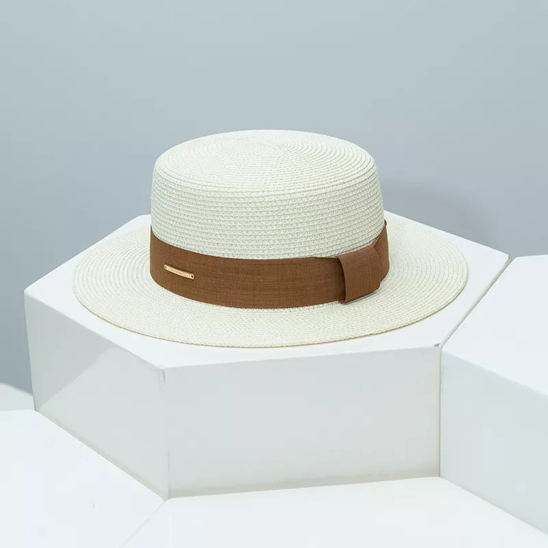 Woven straw boater hat in ivory with a brown ribbon band and gold accent.