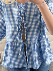 Blue gingham tie-front peplum blouse with voluminous sleeves and tiered hem.