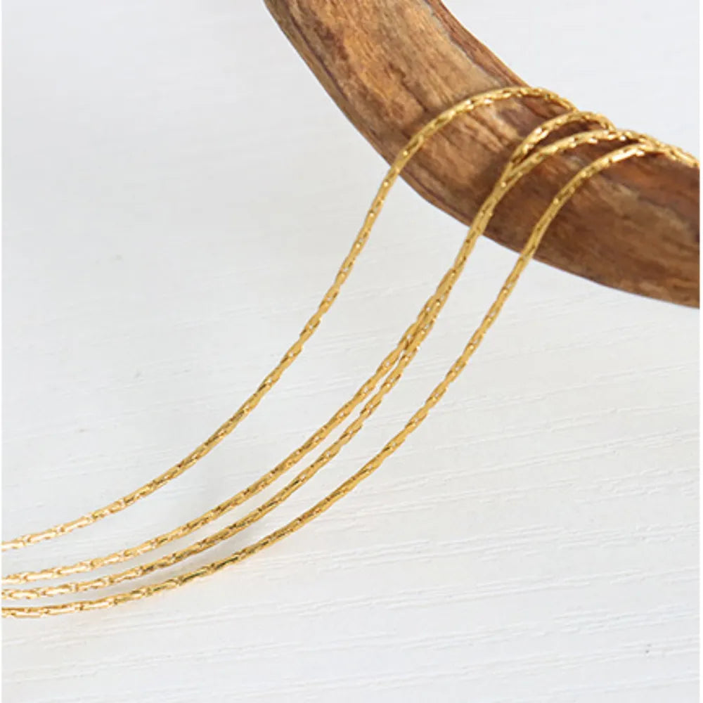 Delicate multi-strand gold-plated chain necklace with a textured finish.