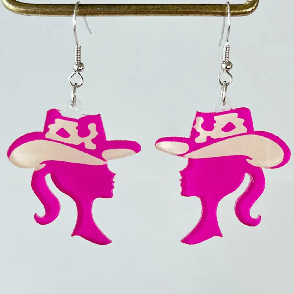 Cowgirl silhouette acrylic drop earrings in hot pink with cream accents.