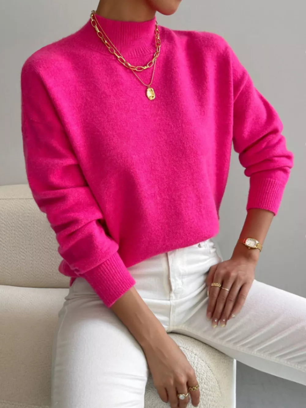 Fuchsia pink mock neck knit sweater with dropped shoulders, acrylic fabric, styled with gold jewelry.