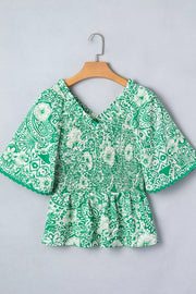 Green floral smocked v-neck polyester overshirt with ruffled sleeves.
