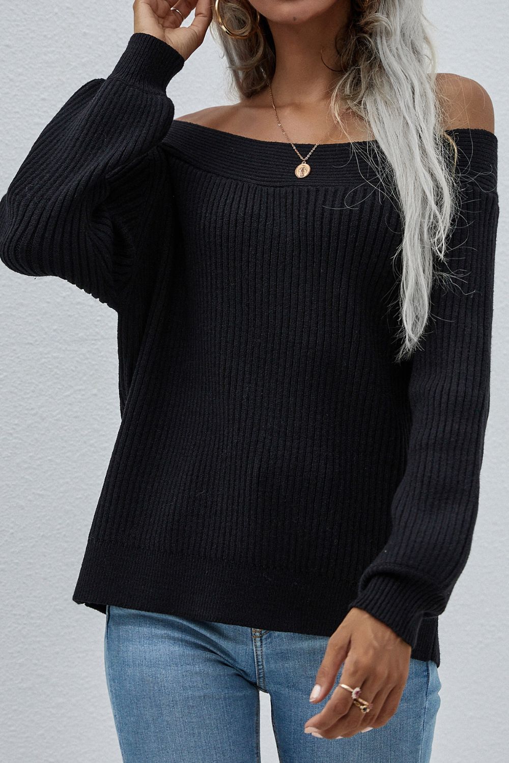 Black ribbed knit sweater with boatneck and puff sleeves, styled off-shoulder.