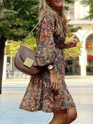 Paisley print balloon sleeve dress in brown with tie waist, worn by a woman with a brown crossbody bag.