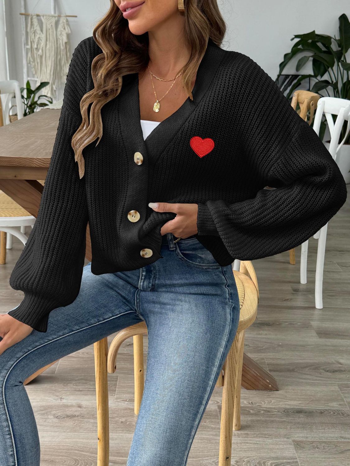 Black buttoned cardigan with balloon sleeves and red heart appliqué detail.