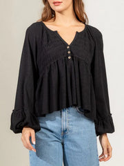 Black textured ribbed peplum blouse with v-neck, buttons, and ruffled cuffs.
