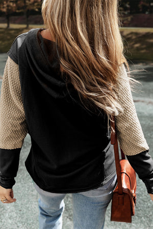 Black and tan colorblock hoodie with textured sleeves and a hood.
