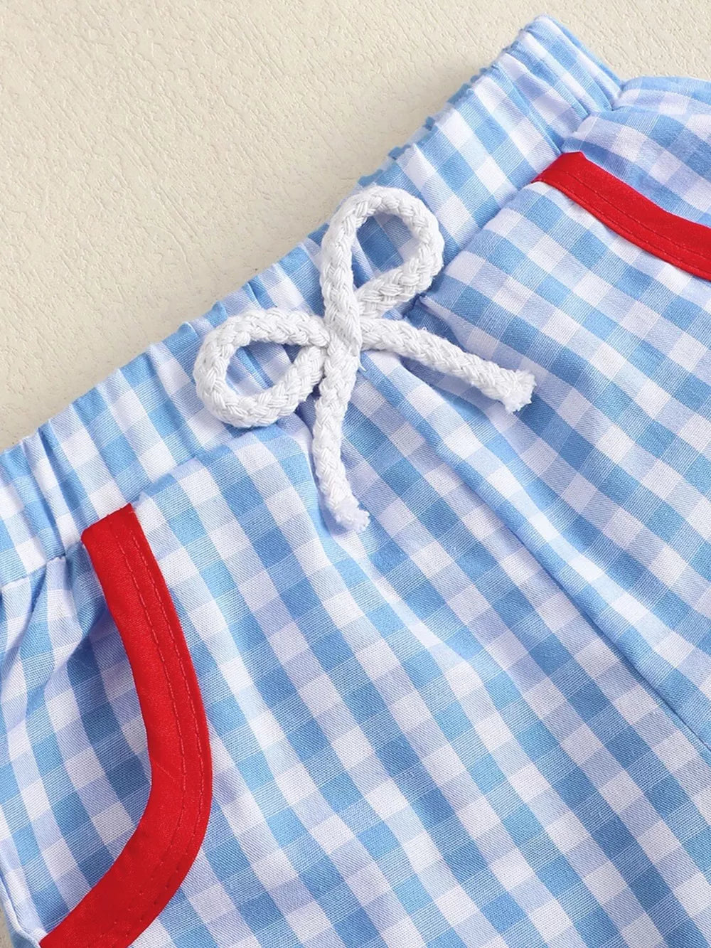 Baby blue gingham shorts with red trim and white drawstring.