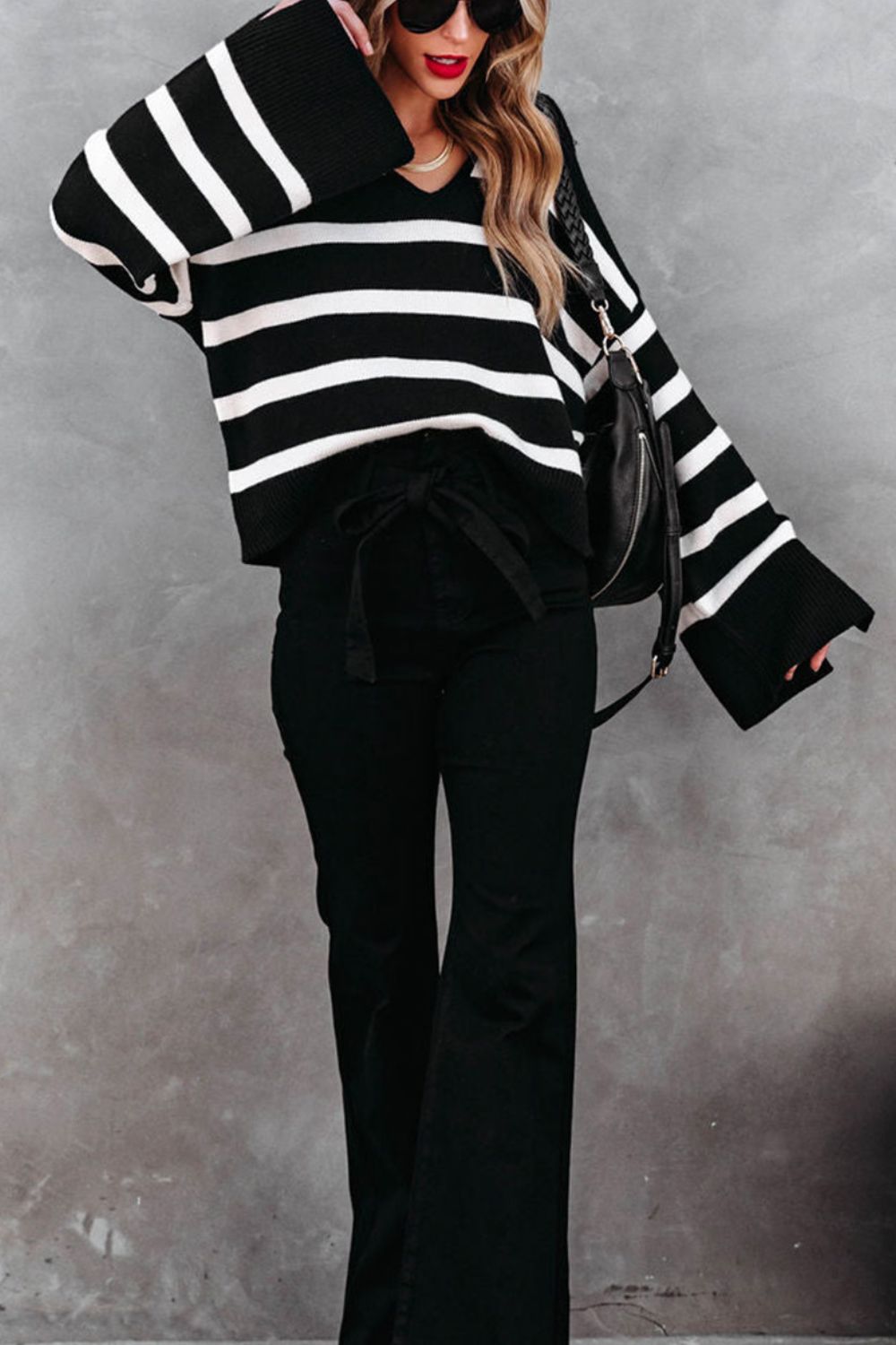Black and white striped knit sweater with wide bell sleeves and a V-neck.