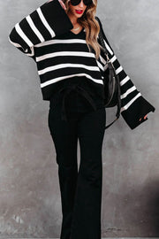 Black and white striped knit sweater with wide bell sleeves and a V-neck.