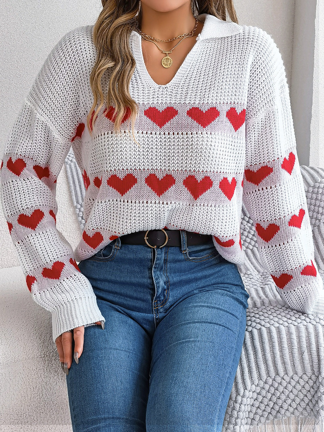 White knit polo sweater with red hearts pattern and striped detail.