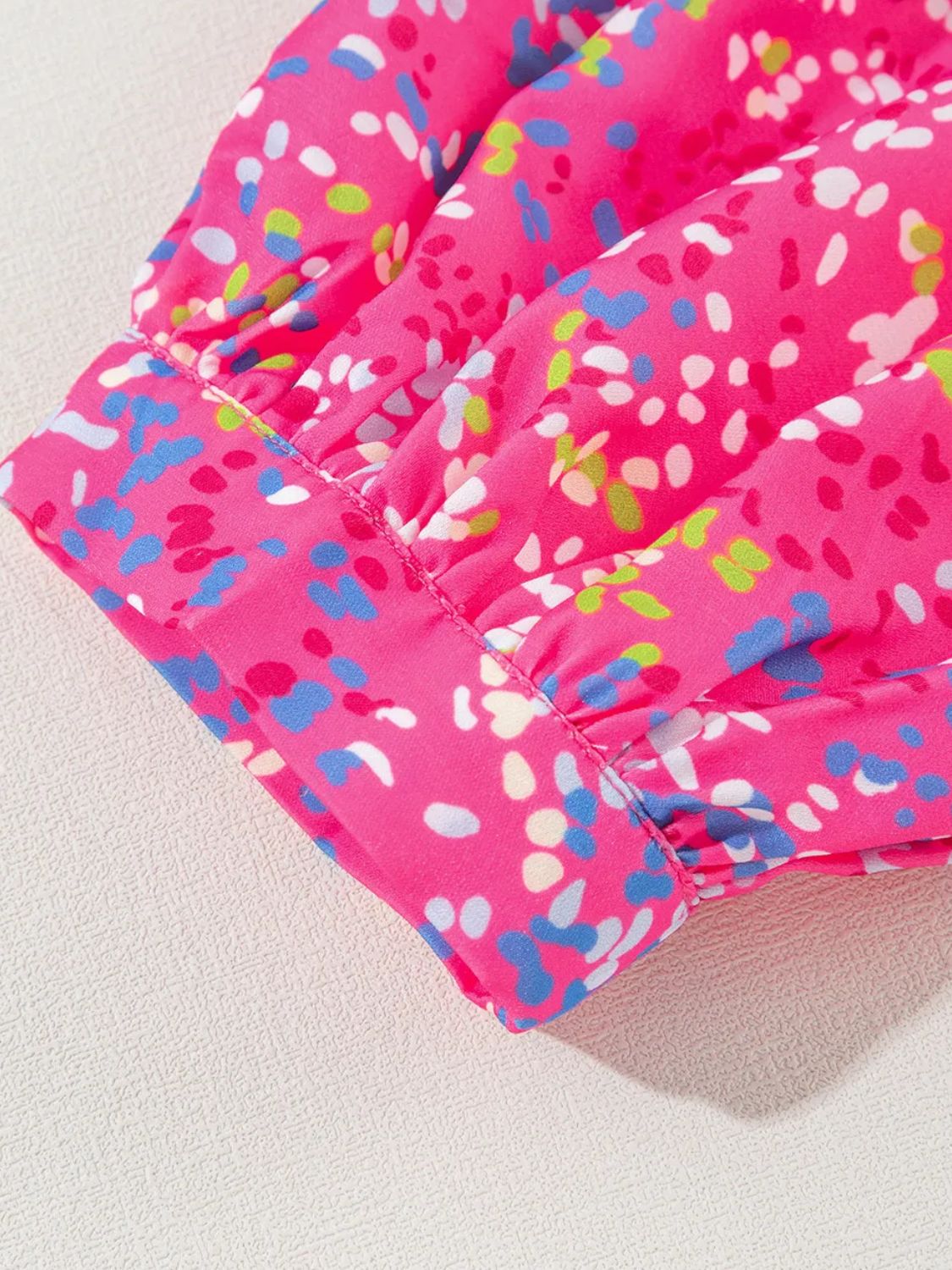 Hot pink blouse with a colorful abstract dot print and ruched mesh sleeves.