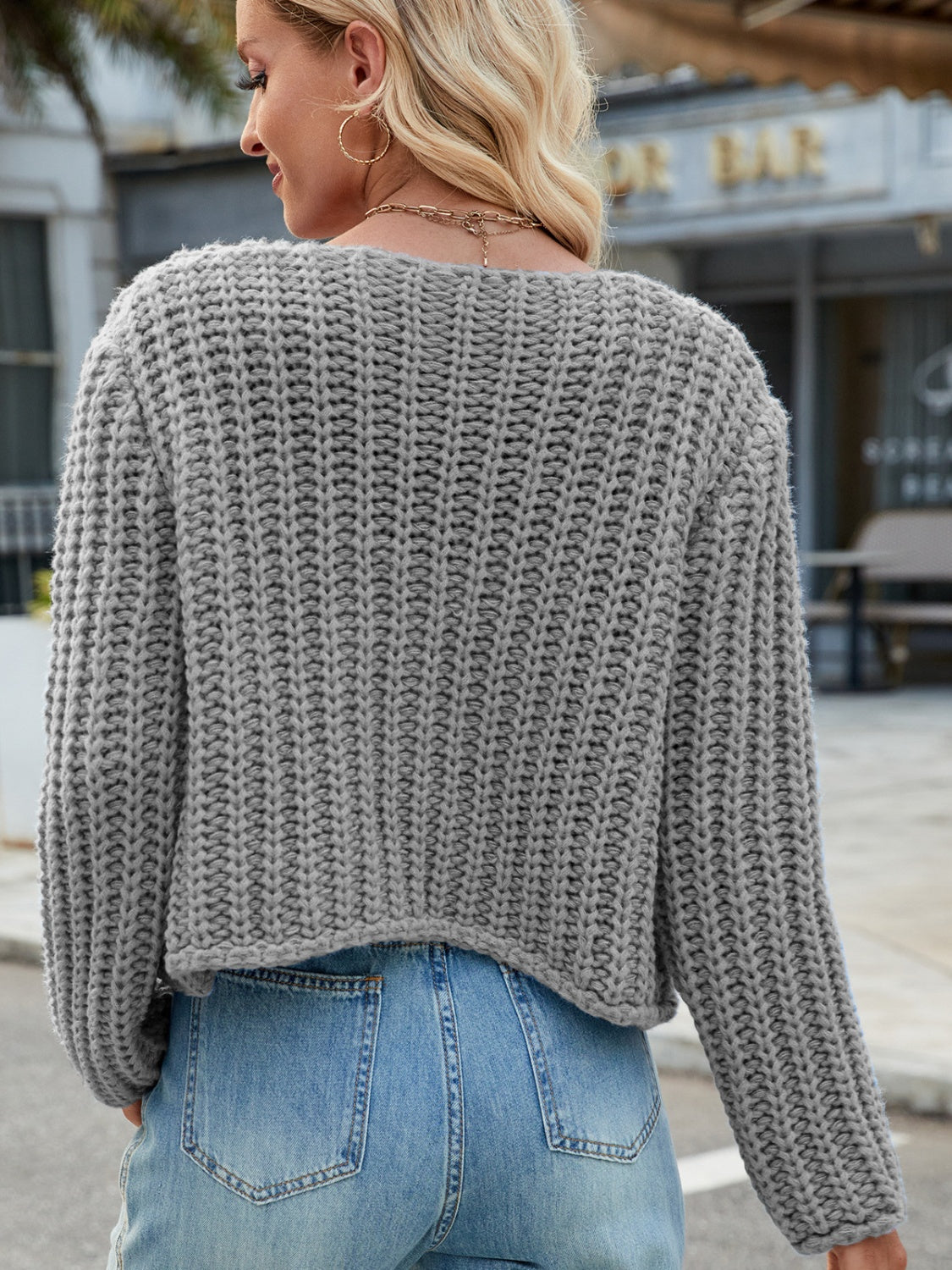 Gray chunky knit acrylic cardigan with gold buttons and pockets.