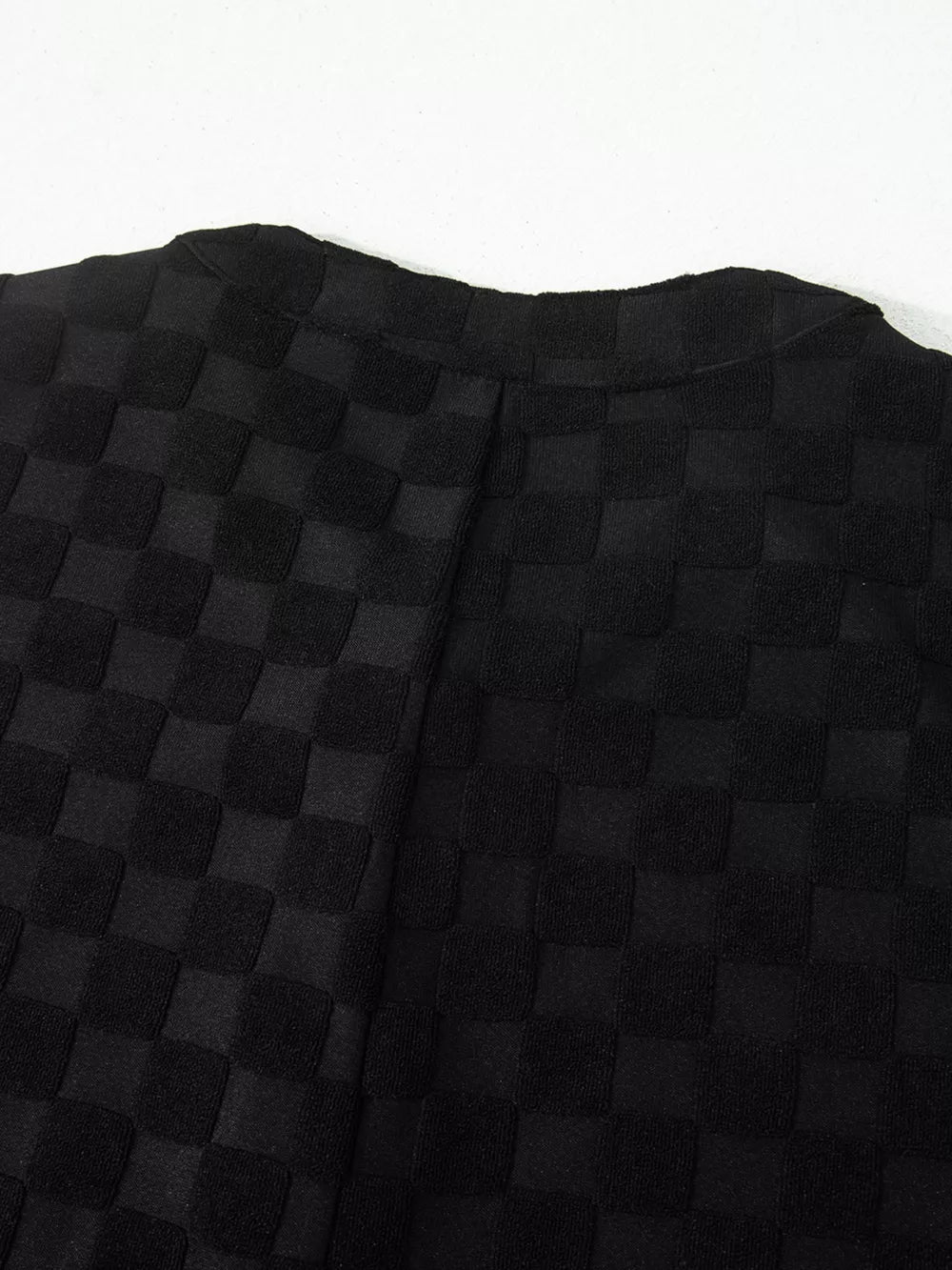 Black checkered wide-leg jumpsuit with button-front detail.
