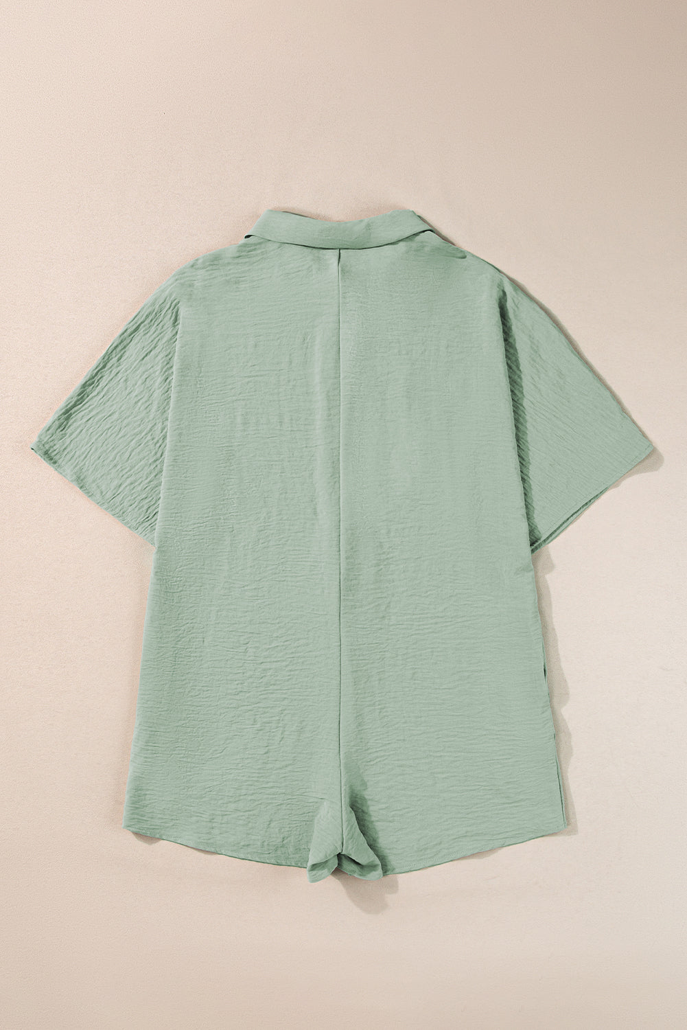 Sage oversized shirt romper with textured fabric and short sleeves.