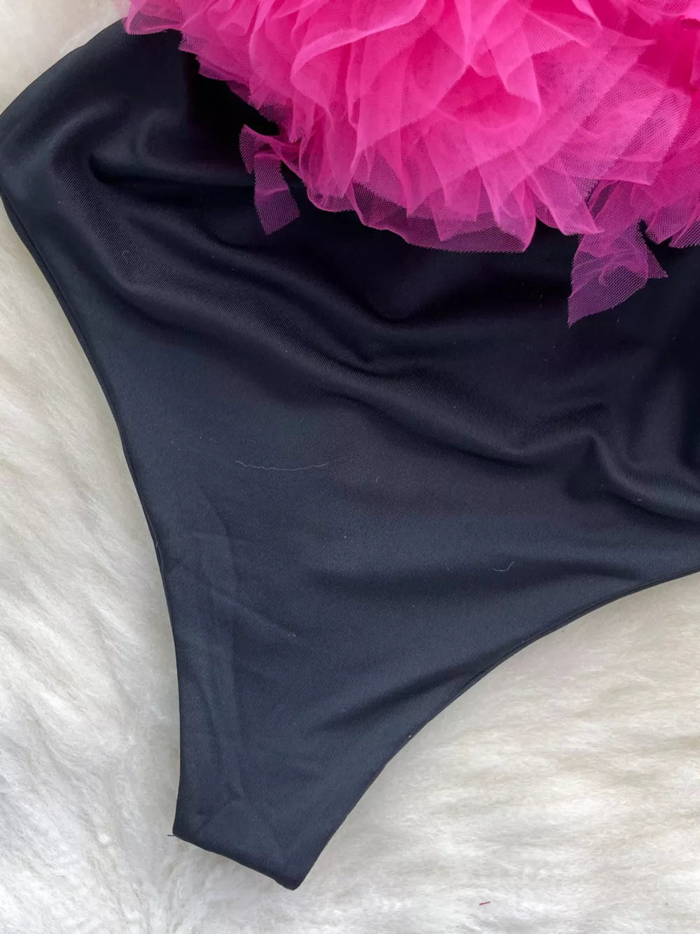 Black bodysuit with pink ruffled tulle detail and V-neck.