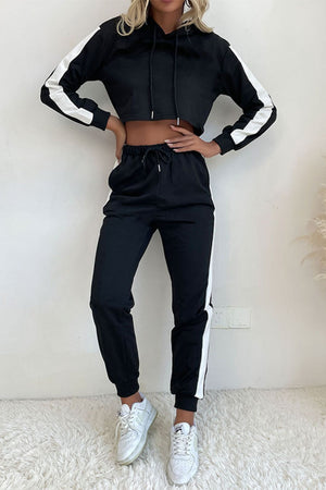 Black cropped tracksuit with white stripe detail on sleeves and pants.