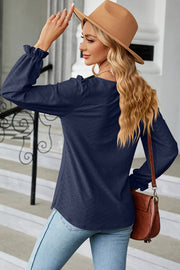 Dark blue textured puff sleeve blouse with ruffled cuffs.
