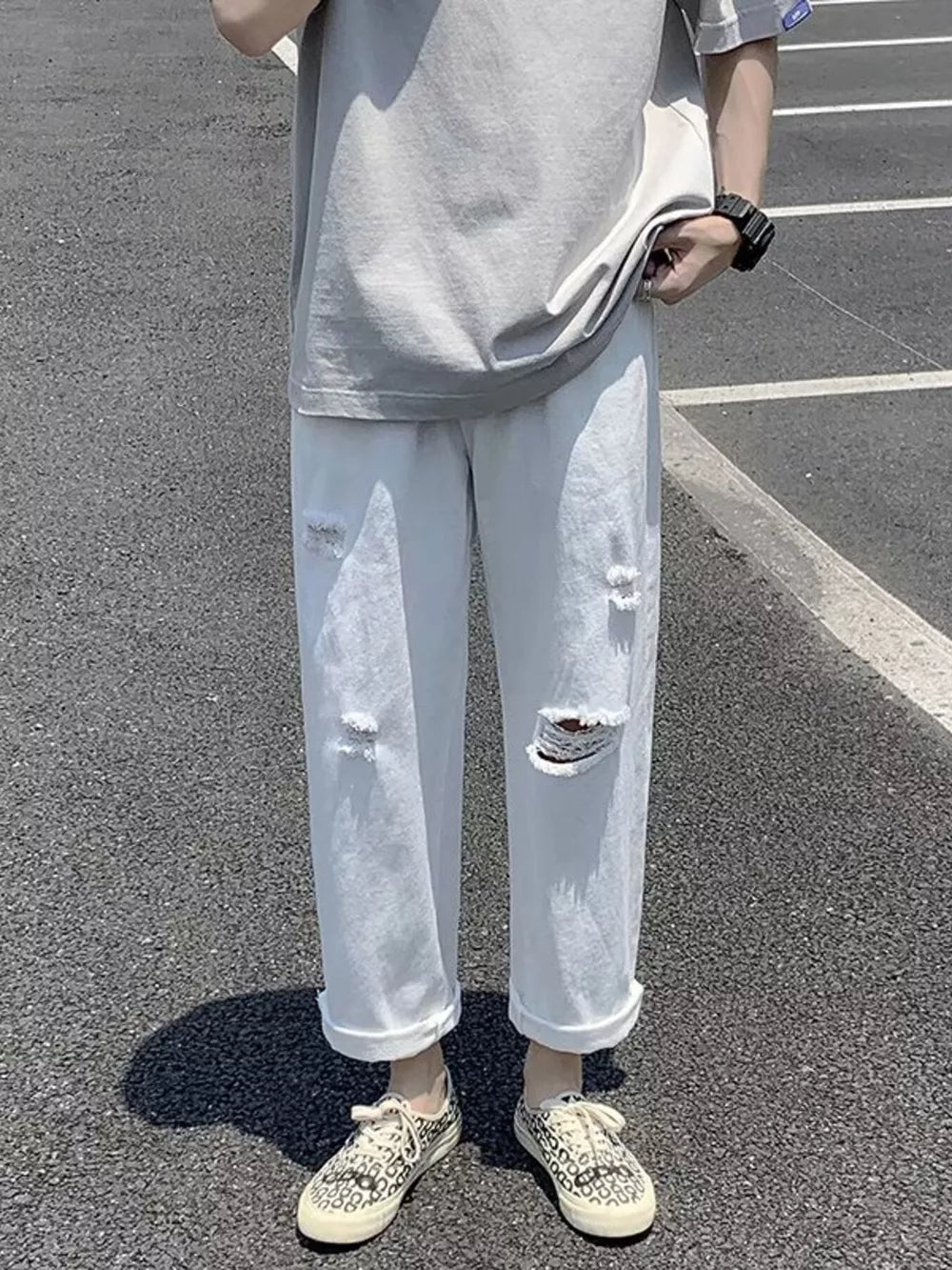 White distressed relaxed fit men's jeans with cuffed hems.