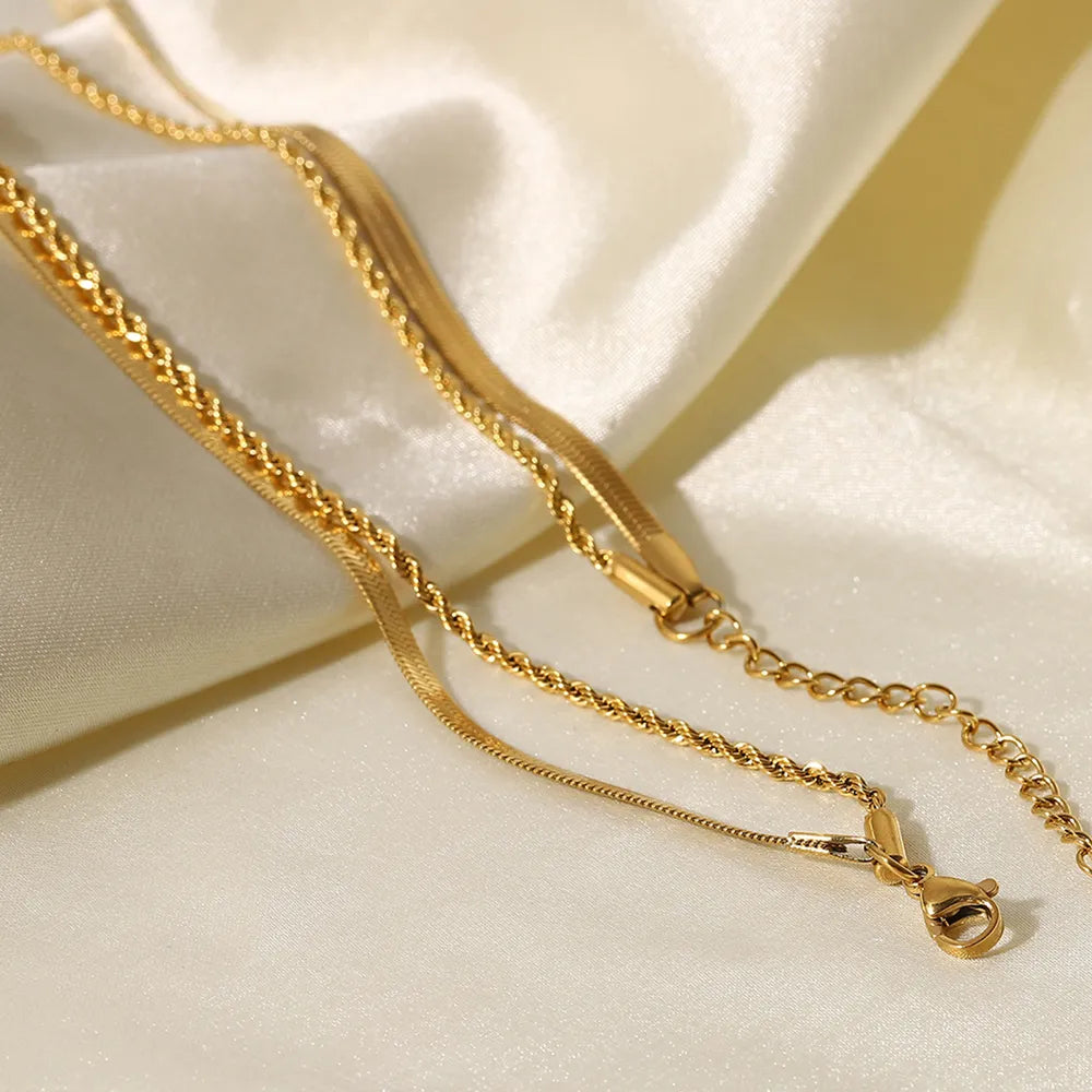 Gold serpentine and rope chain necklaces layered on satin fabric