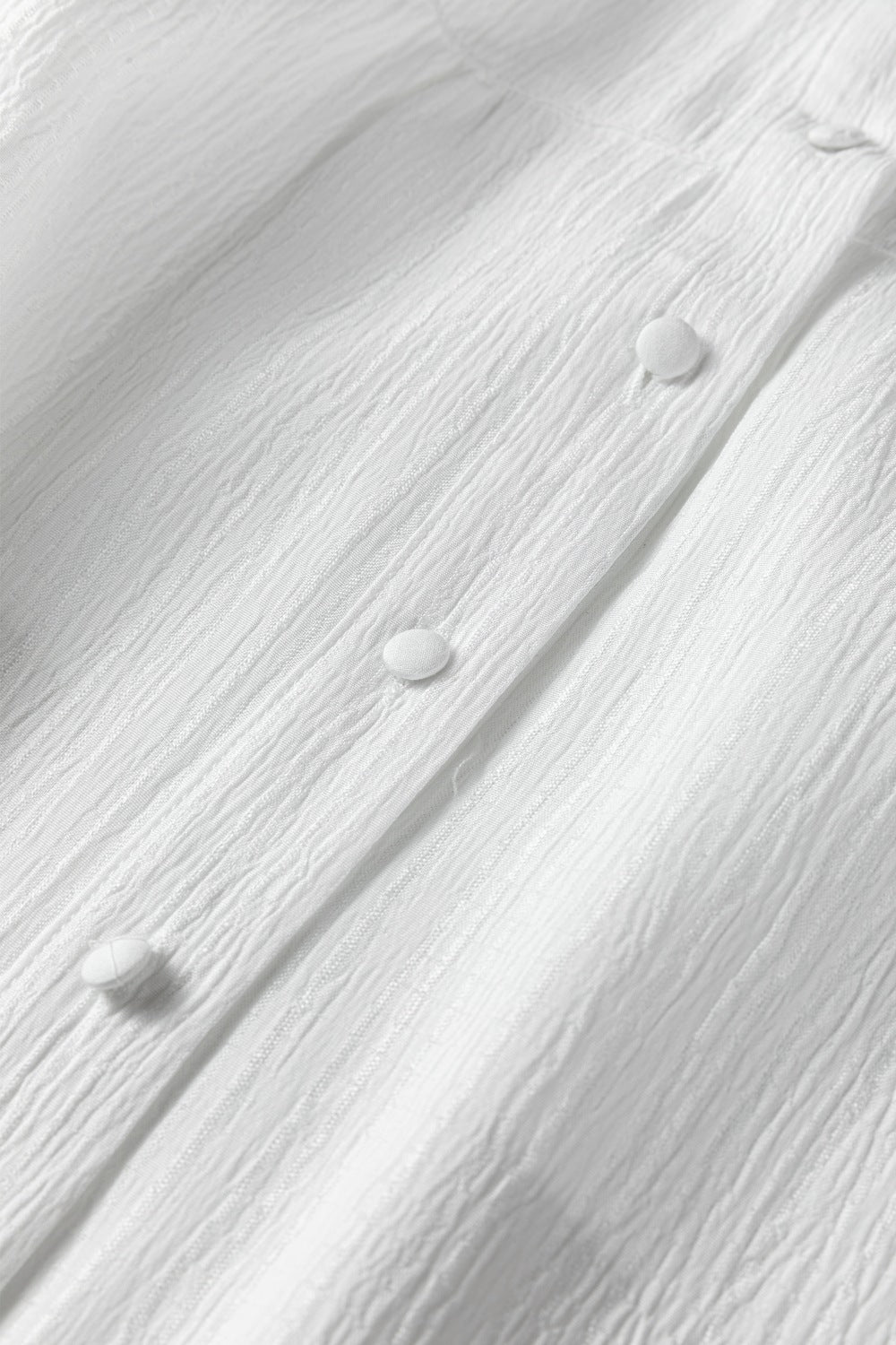 White crinkled texture button-down shirt with elastane, showing fabric detail and buttons.