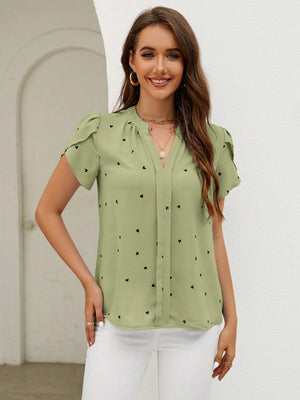 Matcha green blouse with black heart print, puff sleeves, and V-neck.