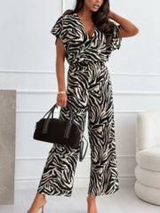 Zebra print wide-leg romper with V-neck and short sleeves, styled with a handbag.