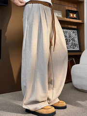 Loose fit sweatpants in khaki with drawstring and pockets, styled with casual shoes.