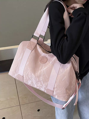 Chic medium blush pink Oxford cloth travel bag with adjustable strap and logo detail.