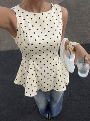 Chic white sleeveless peplum blouse with black polka dots and a round neckline.