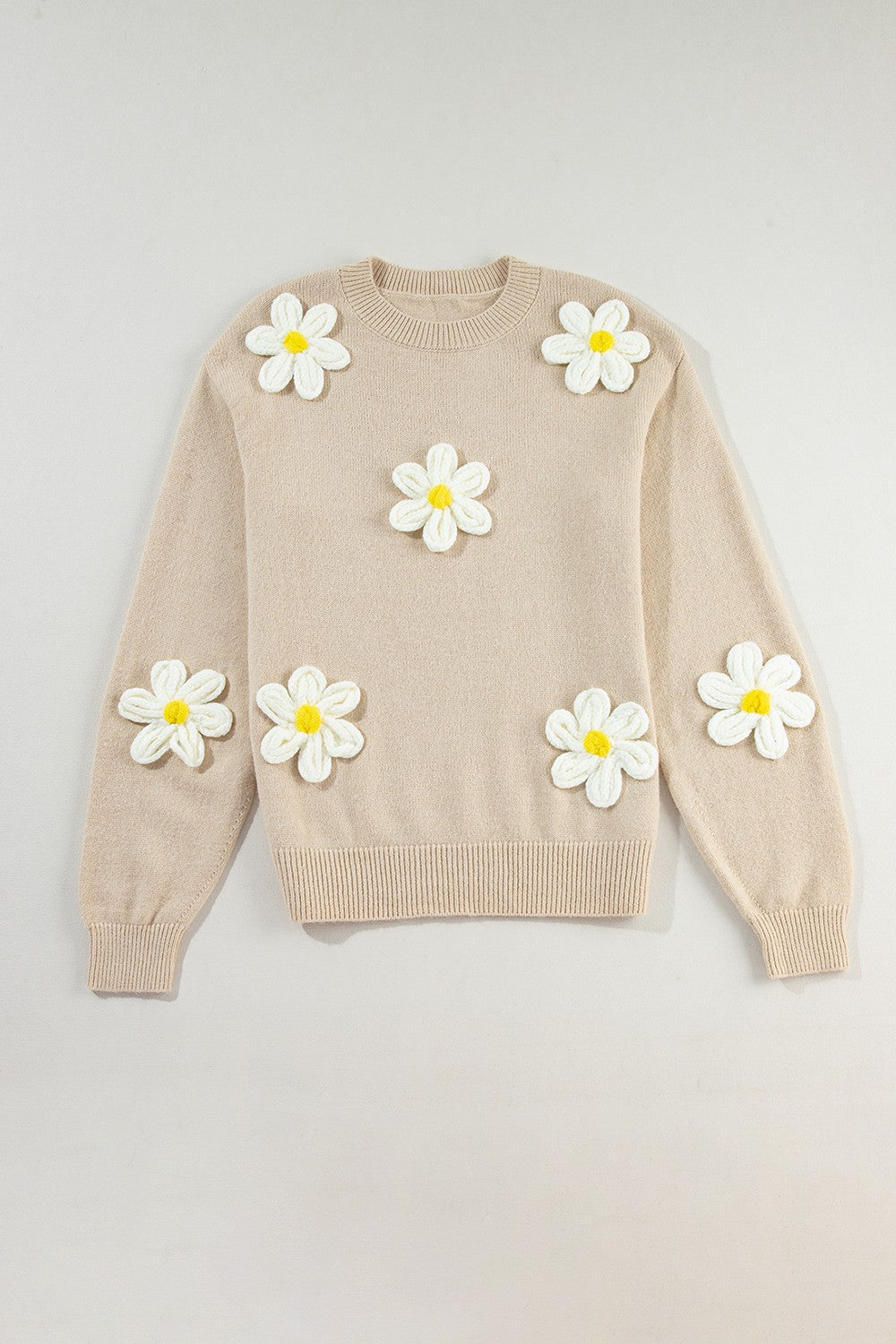 Tan knit sweater with embroidered white and yellow daisies, crew neck, long sleeves.