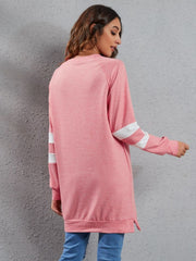 Pink raglan sweatshirt dress with white sleeve stripes, crew neck, and side slits.