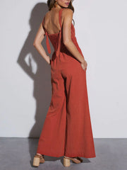 Orange-red tie-strap bodice wide-leg jumpsuit with smocked back and pockets.