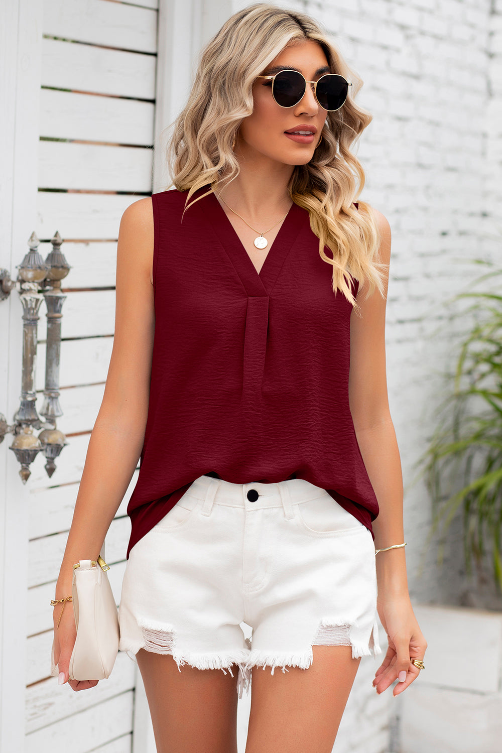 Burgundy textured sleeveless blouse with V-neck and pleated front detail.