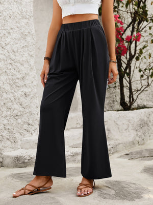 Black wide leg trousers with elastic waist and subtle pleats, styled with sandals.
