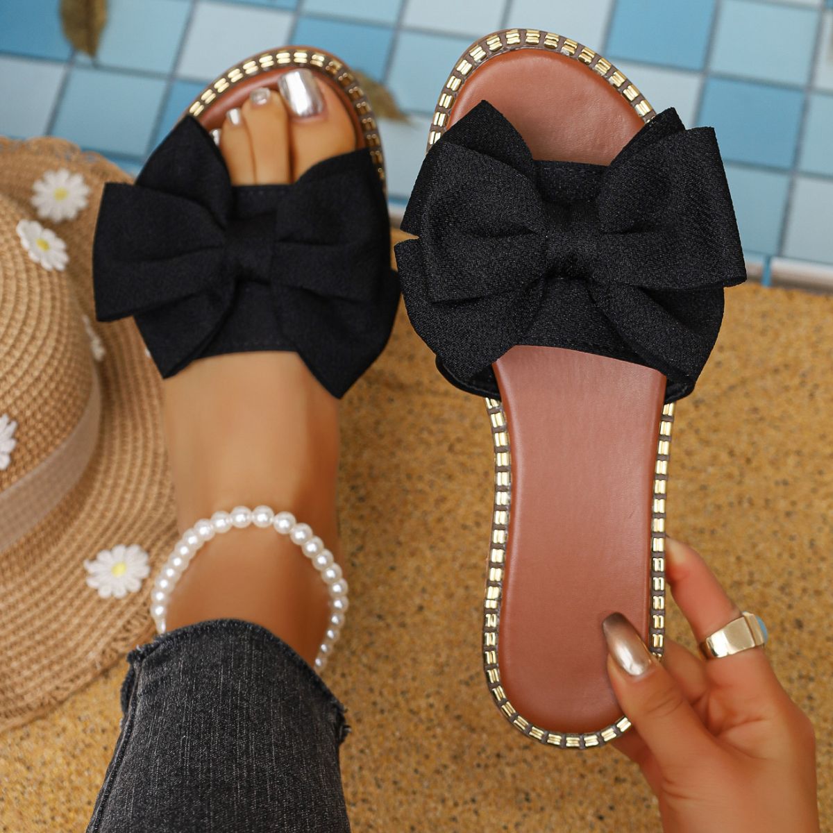 Black bowknot sandals with gold trim, styled with a pearl anklet.