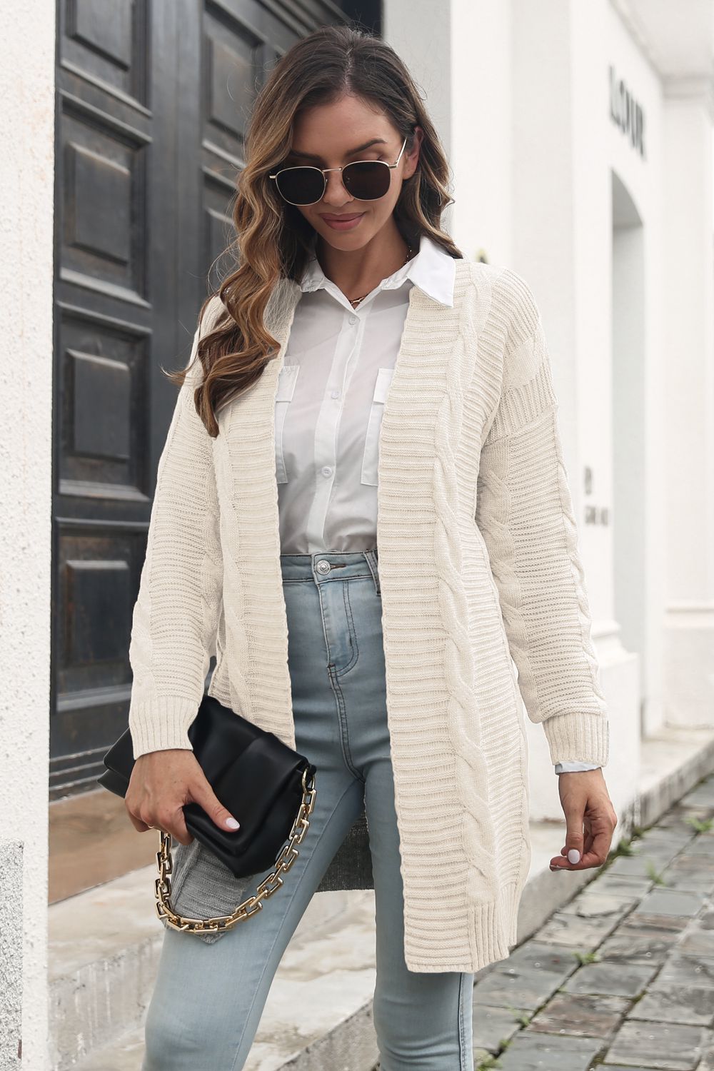 Longline cable knit cardigan in ivory with open front and long sleeves.