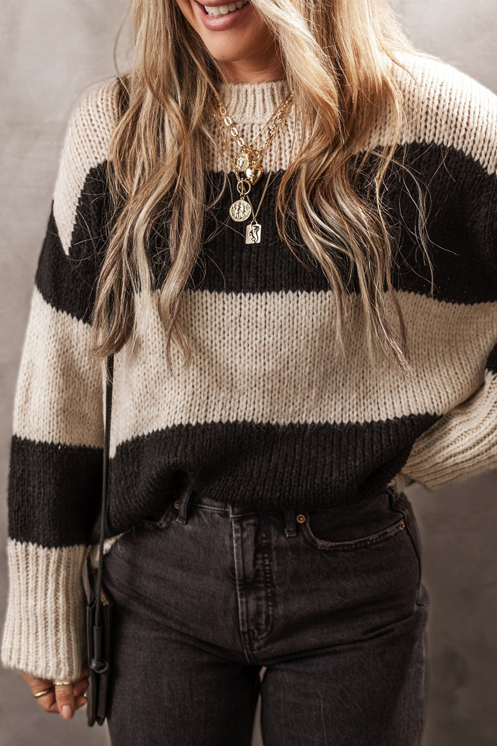 Relaxed knit sweater with bold black and cream stripes, crewneck, and long sleeves.