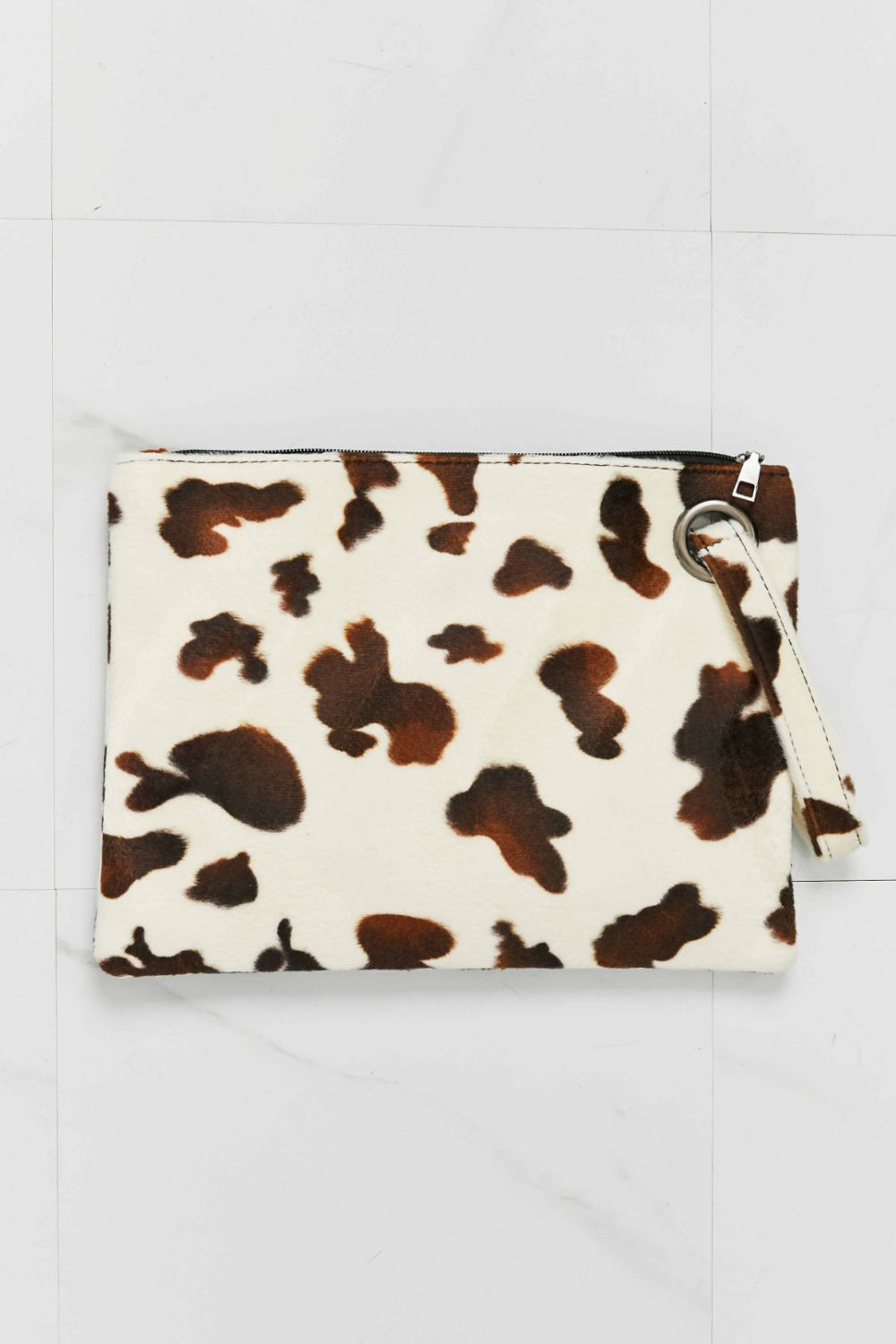Cowhide print clutch bag with wristlet strap in brown and cream.