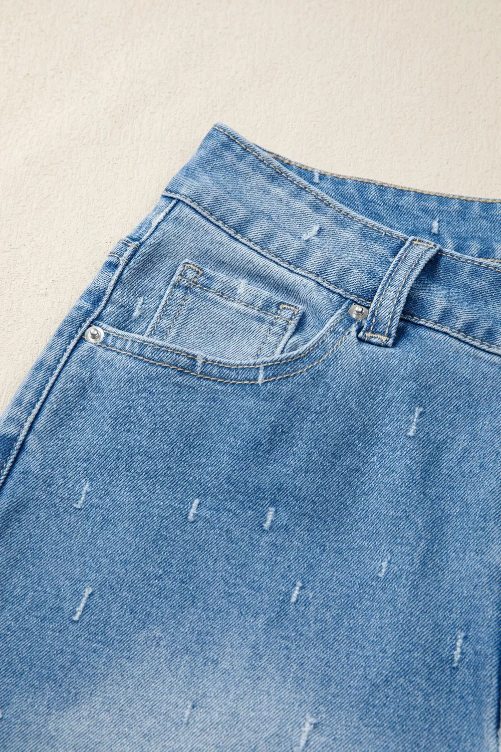 Light wash denim jeans with high-rise waist and distressed details.