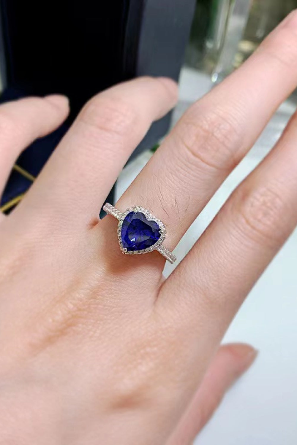Blue heart halo engagement ring with diamond accents on a silver band.