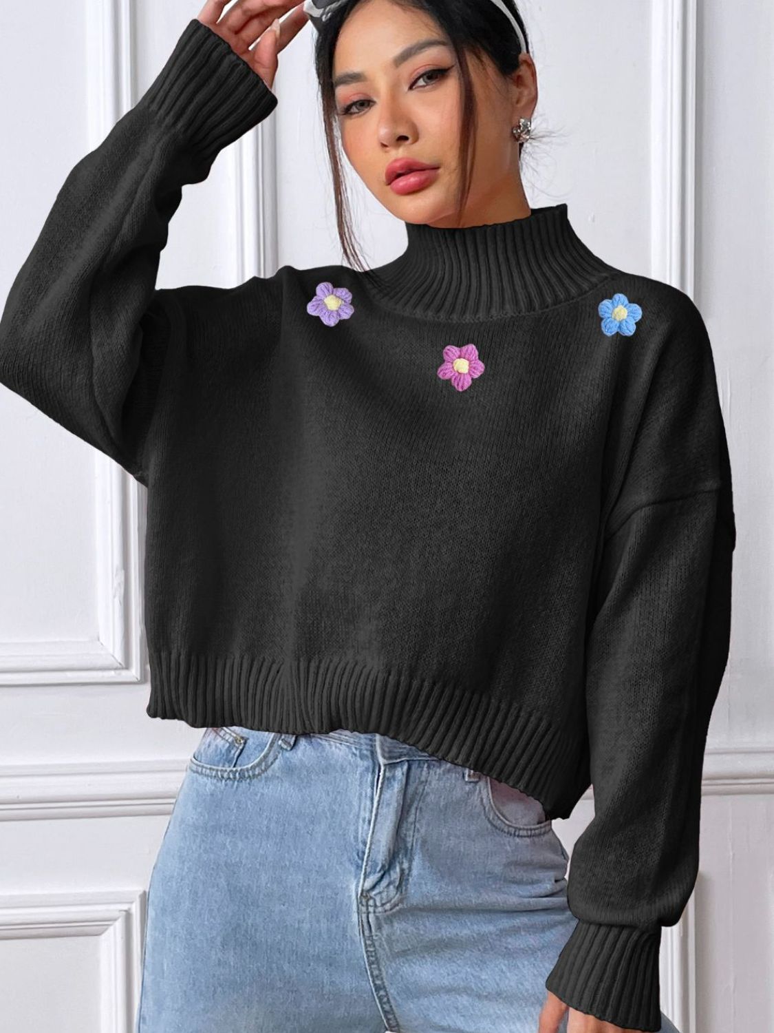 Black cropped turtleneck knit sweater with embroidered floral details and ribbed cuffs and hem.