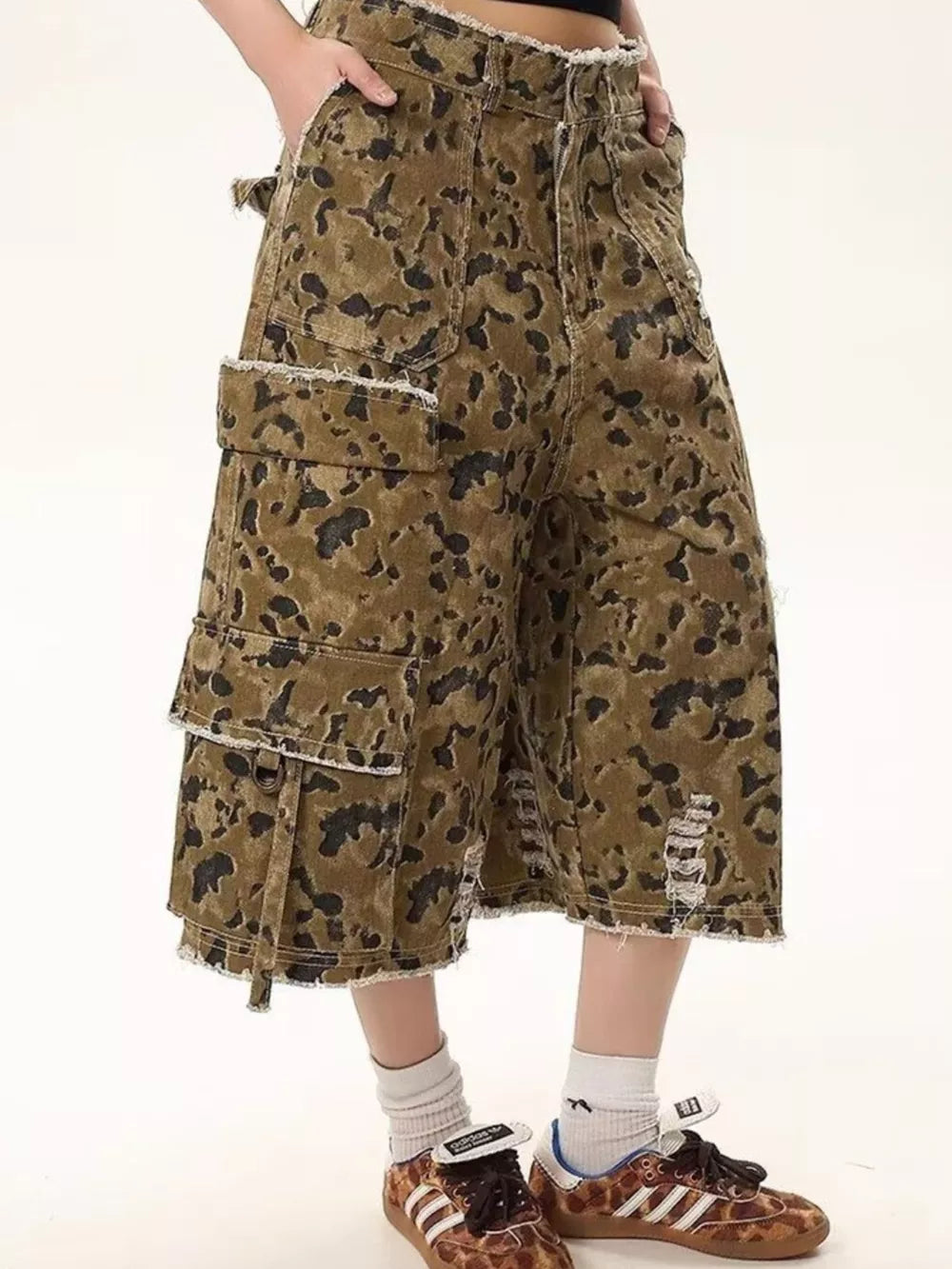 Men's distressed camo denim cargo shorts with frayed hem and pockets.