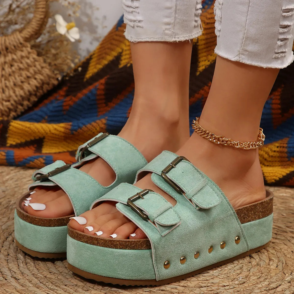 Light green platform slides with double buckle straps and gold stud details.