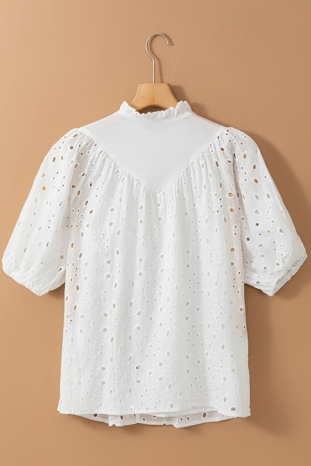 White eyelet puff-sleeve blouse with stand collar and ruffled neckline.
