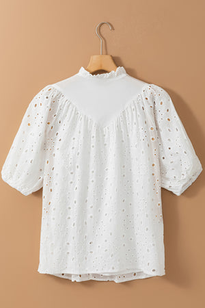 White eyelet puff-sleeve blouse with stand collar and ruffled neckline.